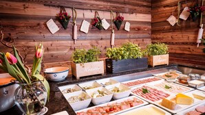 A buffet with various food items and a wooden wall with hanging decorations.