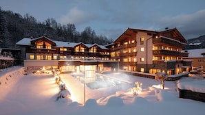 A large, multi-story hotel with a snow-covered courtyard and outdoor hot tub.