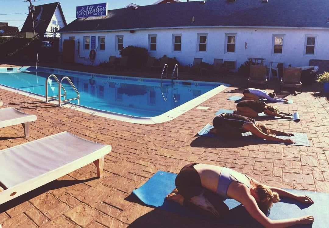 Un área junto a la piscina con sillas de descanso, una piscina y un espacio para yoga.