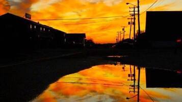 A sunset over a calm body of water reflecting buildings and power lines.