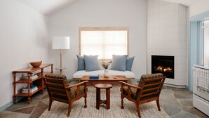 A cozy living room with a fireplace, a sofa, a coffee table, and two chairs. - Daunt's Albatross Motel (Montauk)