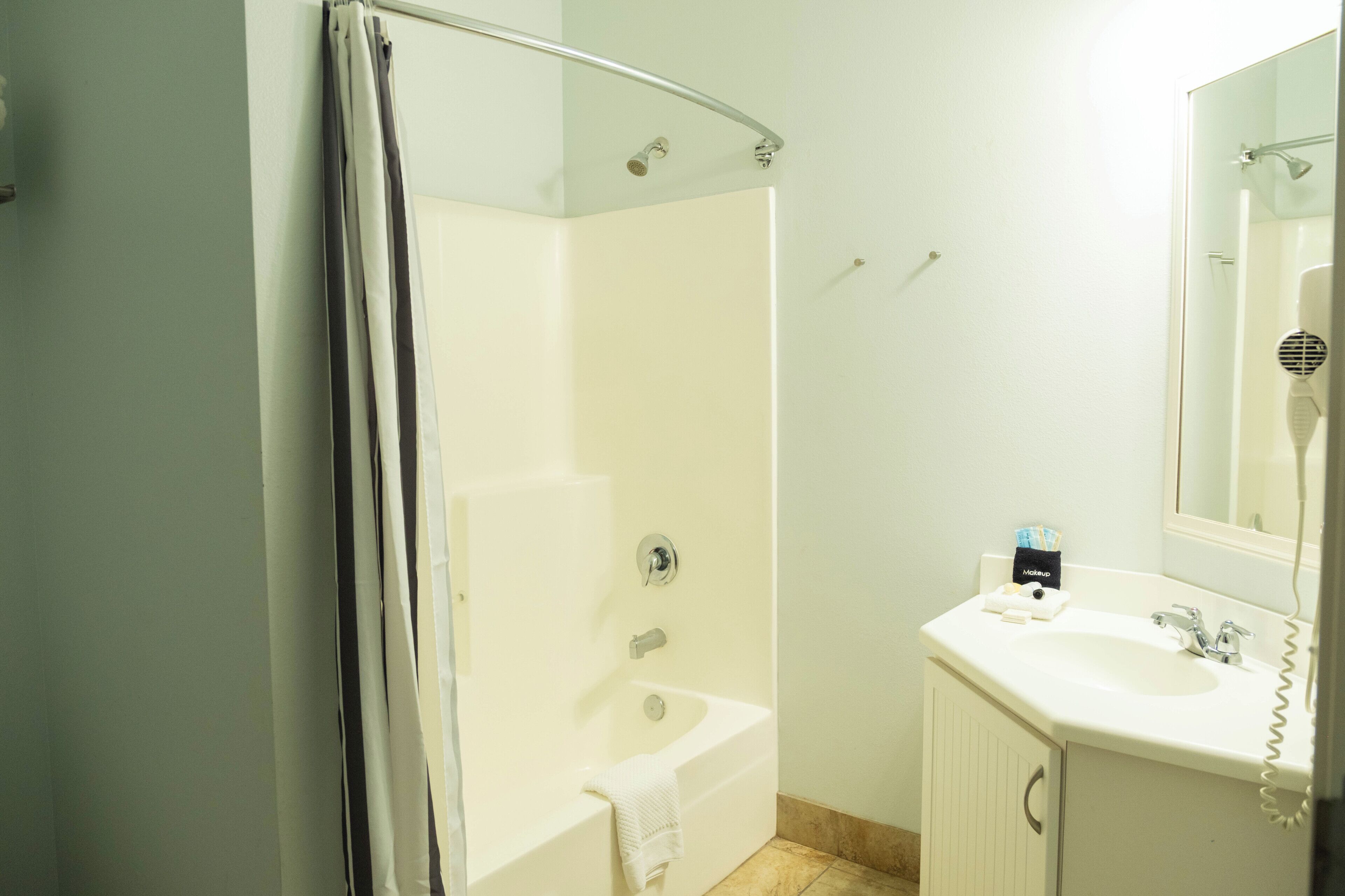A bathroom with a shower, a sink, and a mirror.