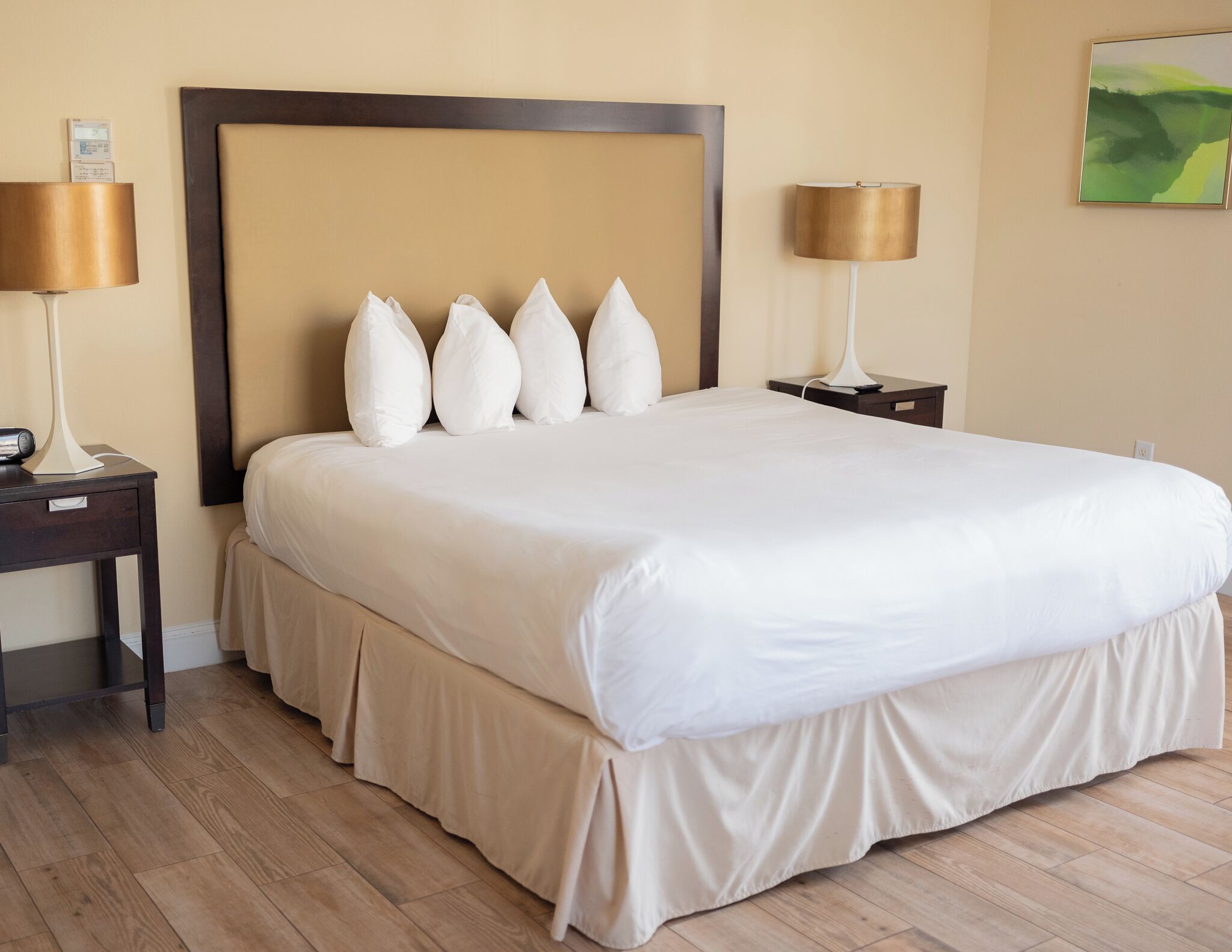 Une chambre d’hôtel avec un grand lit, deux tables de chevet, une tête de lit et une lampe fixée au mur.