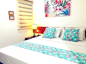 Una camera d'albergo con un letto, un comodino, una lampada e un'opera d'arte floreale appesa al muro.
