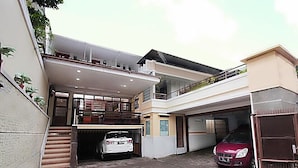 A residential building with a garage, a white car parked inside, and a red car parked outside. - Sm Residence Pasteur (Bandung)