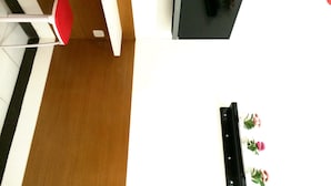 A room with a white desk, a black chair, a white telephone, and a black TV stand with flowers. - Sm Residence Pasteur (Bandung)