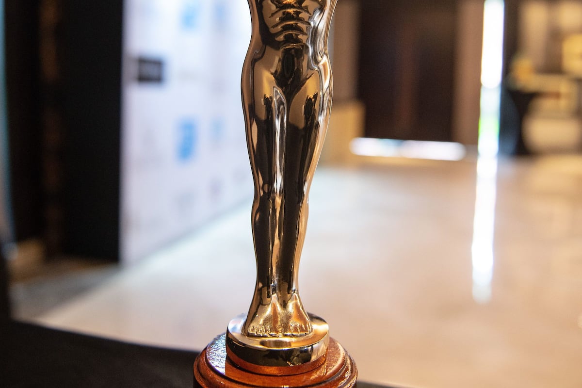 Un trofeo con una figura sosteniendo estrellas, sobre una superficie negra.