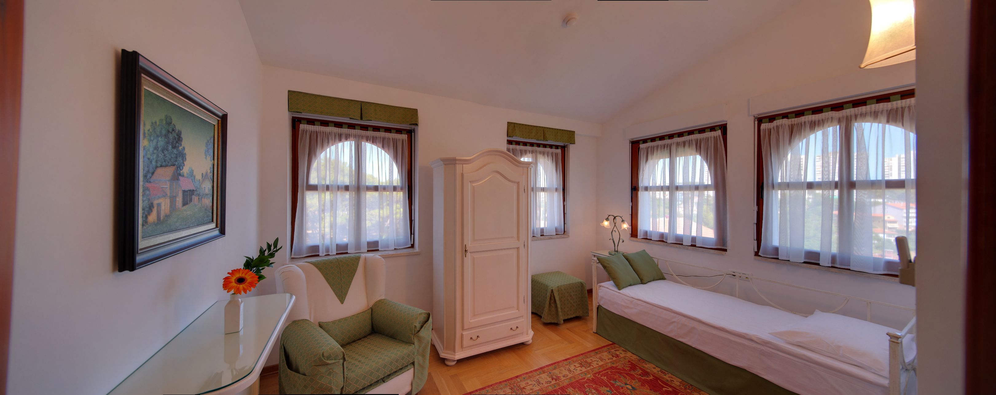A bedroom with a bed, a chair, a wardrobe, and a small table.
