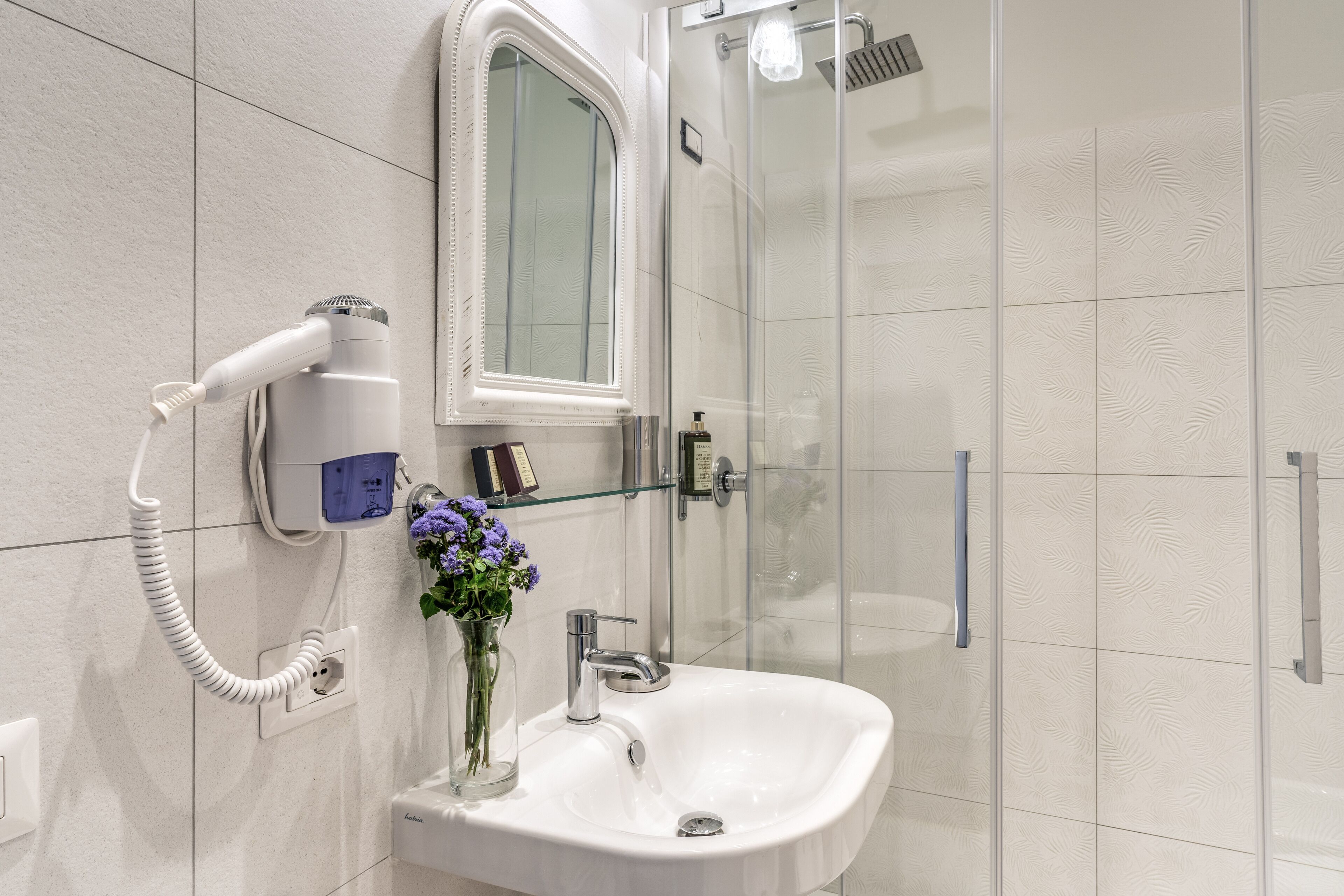 A bathroom with a white sink, a mirror, and a glass shower enclosure.