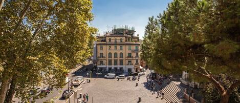A spacious public square with a historic building in the background, surrounded by trees.
