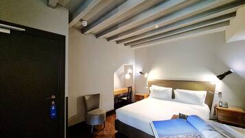 Una habitación de hotel con una cama, una silla, un escritorio y una puerta.