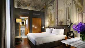 Une chambre d’hôtel avec un grand lit, un bureau, une chaise et un vase de fleurs.