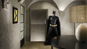 Une pièce comprenant une statue de super-héros, une lampe et un tableau encadré accroché au mur.