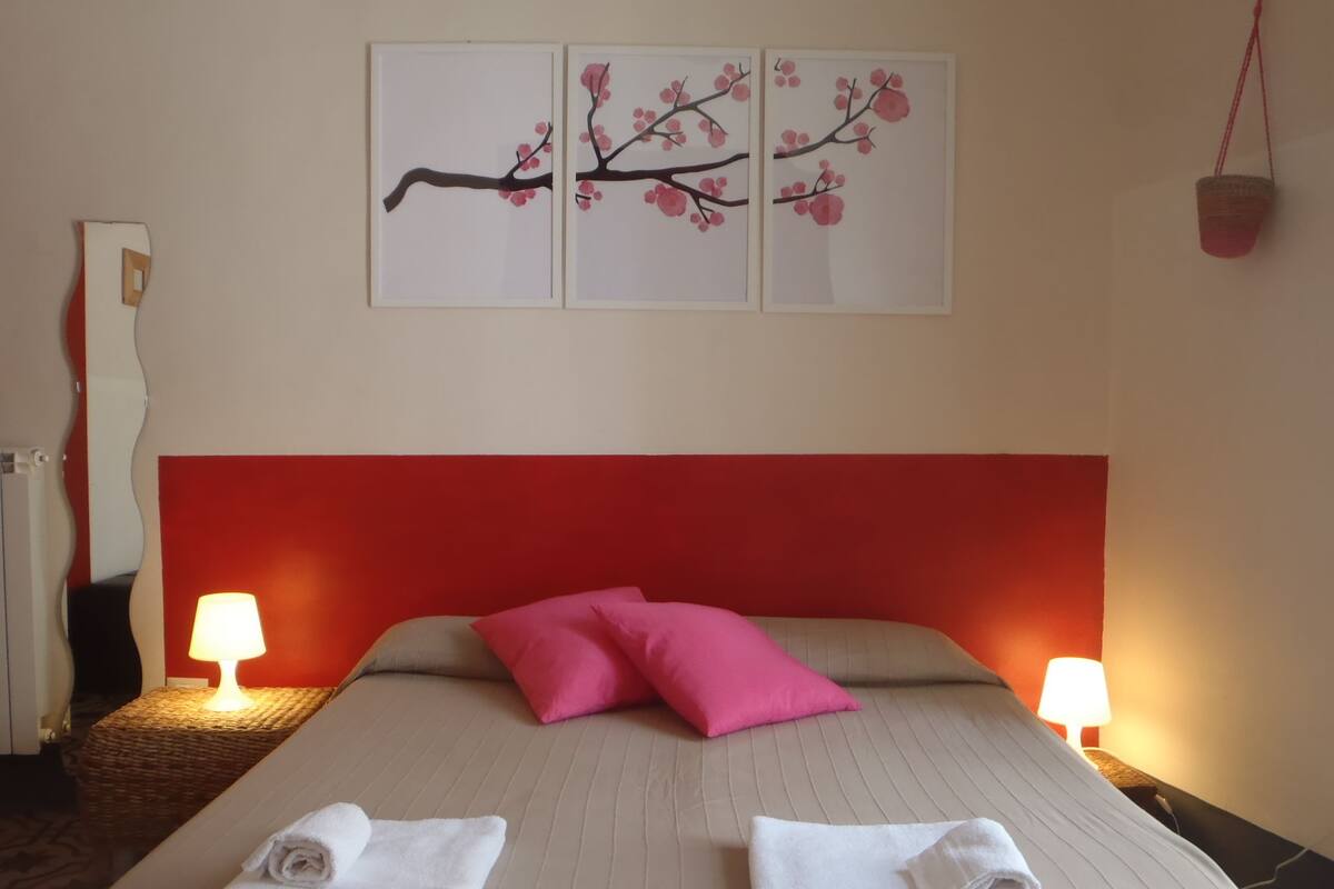 Habitación de hotel con cama, dos almohadas, dos lámparas de noche y una obra de arte en la pared.