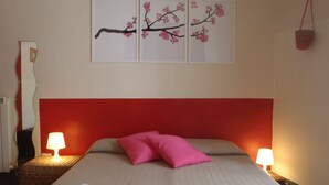 A hotel room with a bed, two pillows, two bedside lamps, and wall art. - Gianluca Rooms (Catania)