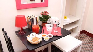 A breakfast setup with a red table, a mirror, a potted plant, and a small shelf with towels. - Gianluca Rooms (Catania)