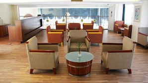 A lobby with a reception desk, seating area with armchairs and sofas, and a large window with curtains. - Sunny Holiday Hotel (Yangon)