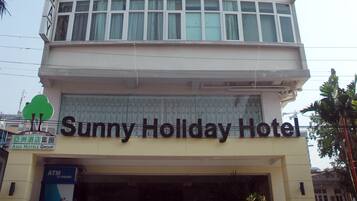 A multi-story building with the signage "Sunny Holiday Hotel" at the top and "Asia Hotels Group" at the bottom.