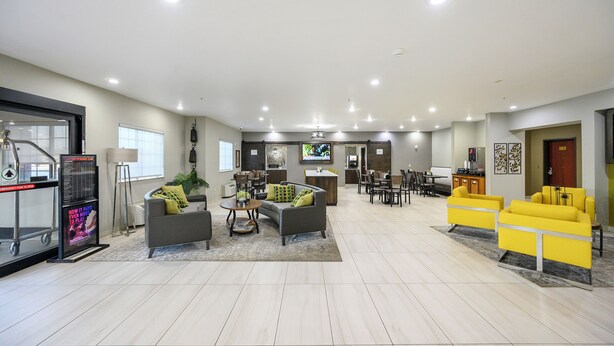 A spacious living area with a grey sofa, yellow armchairs, a coffee table, and a TV.