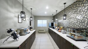 Una cocina moderna con una encimera amplia, una cafetera y una vitrina con productos alimenticios.
