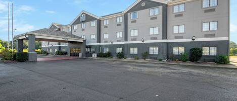 A multi-story hotel with a covered entrance and a parking lot.