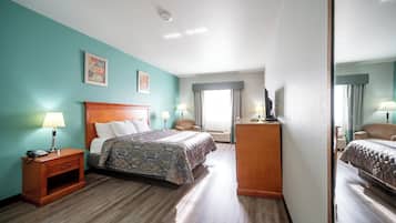 A hotel room with a bed, bedside tables, a dresser, and a large mirror.