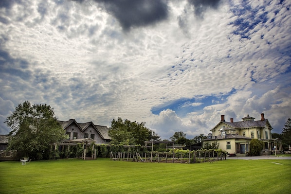 A large, two-story house with a well-maintained lawn and a pergola with vines.