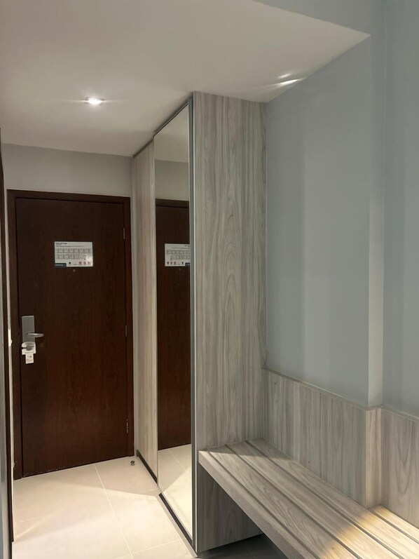 A modern hotel room with a wooden door, a mirror, and a bench. - AlphaPark Hotel (Goiania)