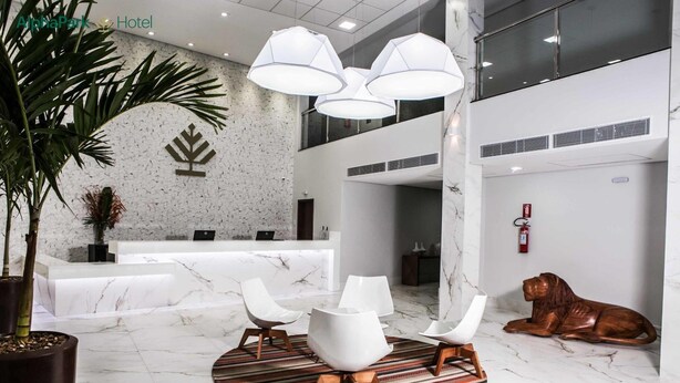 Un vestíbulo de hotel con mostrador de recepción, sillas modernas, una planta en maceta grande y una estatua de león.