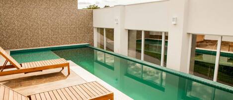 A modern outdoor pool area with wooden loungers and a clear view of the pool.