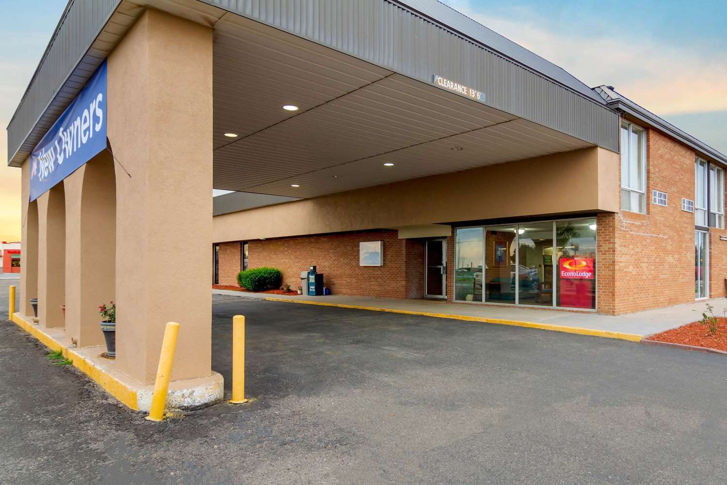 A hotel entrance with a clear sign indicating a clearance of 13'6'.