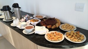 Una mesa de buffet con diversos alimentos, como pasteles, bollería y bebidas.