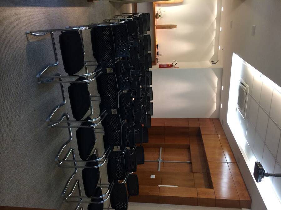 A row of black chairs with metal frames, arranged in a row on a carpeted floor.