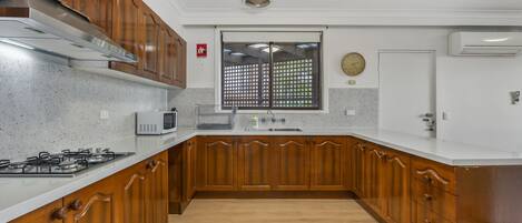 Una cocina con armarios de madera, una campana extractora de acero inoxidable, un microondas y un ventanal con vistas.