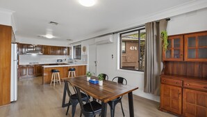 Una cocina moderna con armarios de madera, una isla central y un comedor con mesa y sillas de madera.
