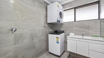 Un bagno compatto dotato di lavatrice e asciugatrice integrate, lavabo e finestra.