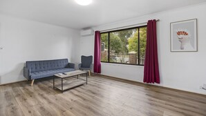 Una sala moderna con un sofá gris, una mesita y una ventana con cortinas.