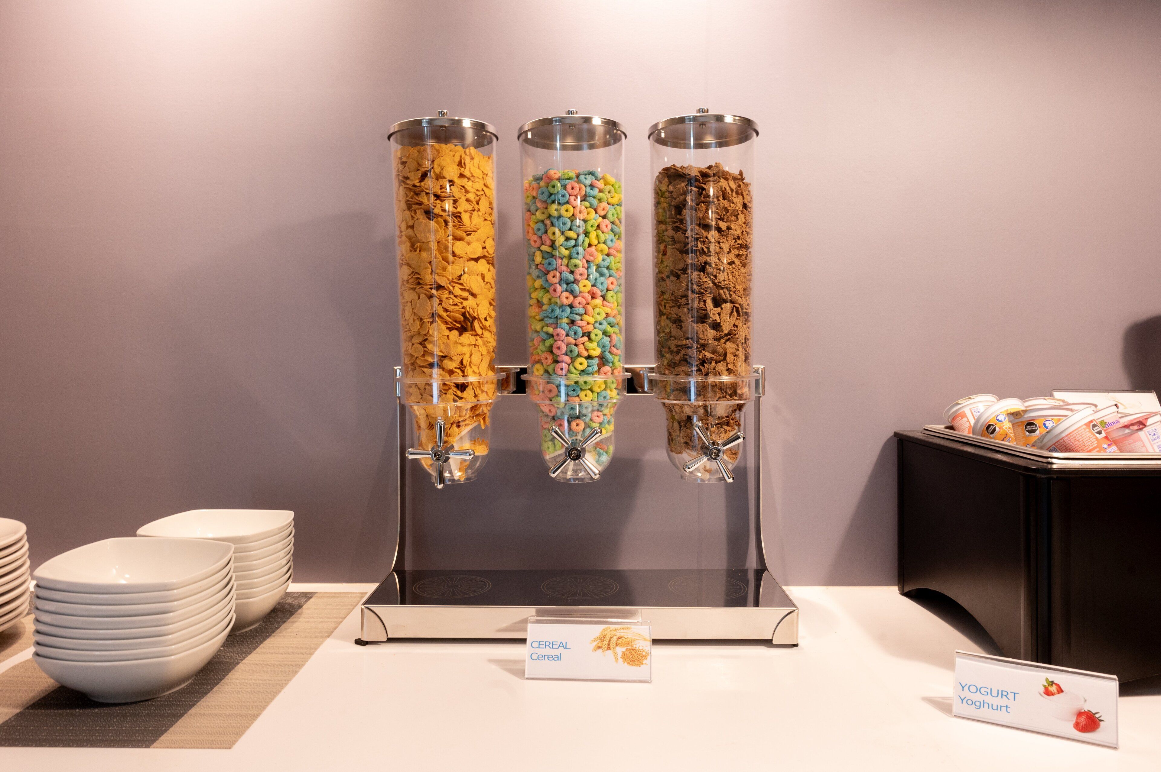 A self-serve cereal and yogurt station with three dispensers.