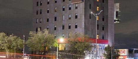 A modern hotel with a flat roof, multiple floors, and a sign reading "Hotel Satellite."