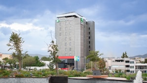 A Holiday Inn Express hotel with a modern design, located near a body of water with a fountain. - Holiday Inn Express Mexico City Satelite by IHG (Naucalpan)