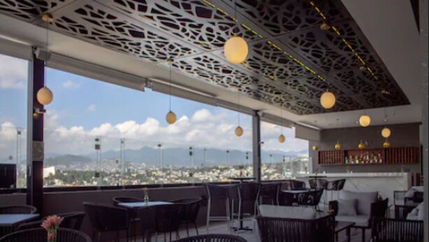 An outdoor dining area with tables and chairs, a view of a cityscape, and a decorative ceiling. - Holiday Inn Express Mexico City Satelite by IHG (Naucalpan)