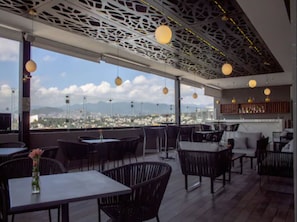 An outdoor dining area with tables and chairs, a view of a cityscape, and a decorative ceiling. - Holiday Inn Express Mexico City Satelite by IHG (Naucalpan)
