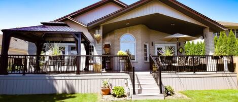 A two-story building with a covered patio area, outdoor seating, and potted plants.