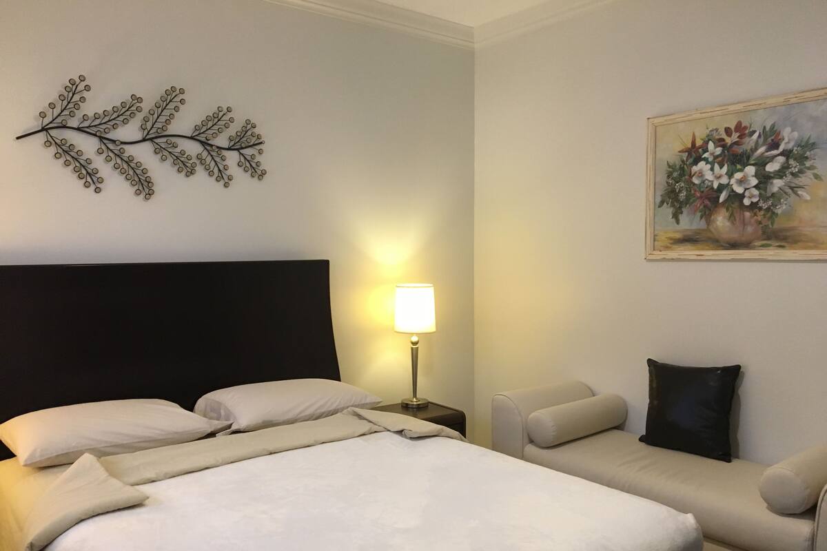 Een hotelkamer met een bed, een nachtkastje met lamp, een bank en een decoratie aan de muur.