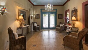 A spacious foyer with wicker furniture, a chandelier, and a blue door leading outside. - Hotel San Marco (Santo Domingo)