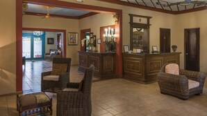 A spacious lobby with wicker furniture, a reception desk, and a ceiling fan. - Hotel San Marco (Santo Domingo)