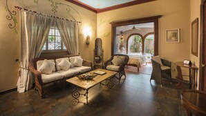 A cozy room with a wicker sofa, a wooden coffee table, and a wicker armchair. - Hotel San Marco (Santo Domingo)