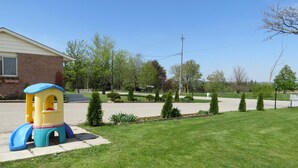 A residential area with a well-maintained lawn, a children's play structure, and a brick house. - Newburg Inn Motel (Township of Wilmot)