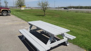 A picnic table in a parking lot with a grassy field and a road in the background. - Newburg Inn Motel (Township of Wilmot)