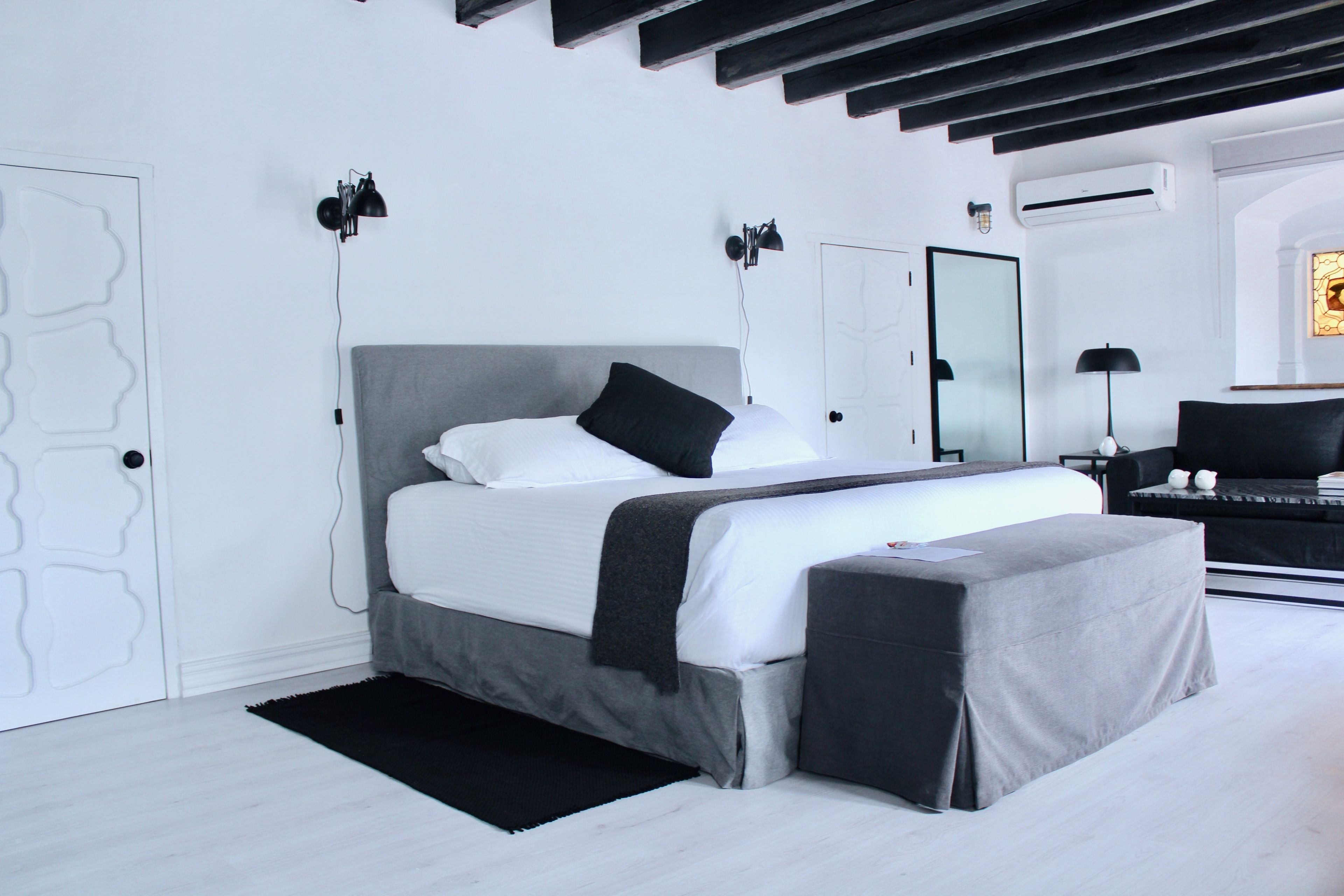 A modern bedroom with a large bed, bedside tables, a desk, and a chair.